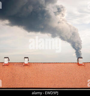 Riesige dunkle Rauch Anhebung von einem Kamin, braun Dach gefliest Stockfoto