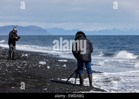 Fotografen, die Fotos von Eisbergen Abwasch am schwarzen Sandstrand am Jökulsárlón Island Stockfoto