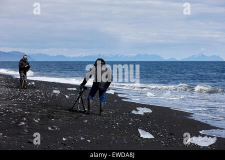 Fotografen, die Fotos von Eisbergen Abwasch am schwarzen Sandstrand am Jökulsárlón Island Stockfoto