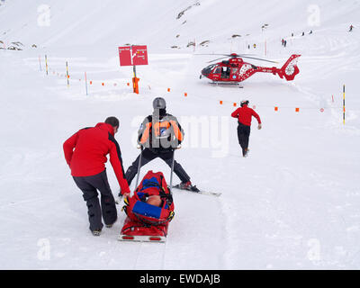 Rettungspersonal trägt dazu bei, dass ein verletzter Skifahrer im Skigebiet von Zermatt in den Schweizer Alpen. Stockfoto