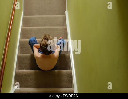 Ein Kind sitzt auf der Treppe mit dem Kopf in seine Hände suchen verärgert Stockfoto