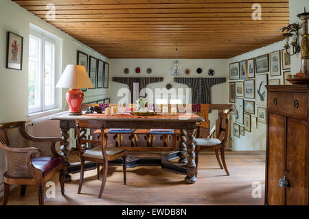 Großer Esstisch aus Holz auf ersten Stock Treppenabsatz mit antiken Schrank und turkmenische Mäntel hingen als Wanddekorationen Stockfoto