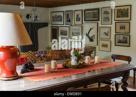 Blumenstrauß mit Rosen und Kerzen am großen Esstisch aus Holz bei der Landung mit indischen Quilt drapiert über das Geländer Stockfoto