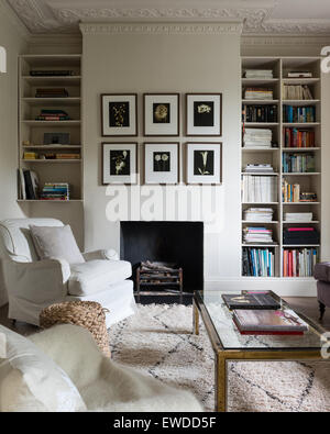 Paar Sessel im Wohnzimmer mit Couchtisch aus Glas gekrönt, Alkoven-Buch-Regal und Kamin Stockfoto