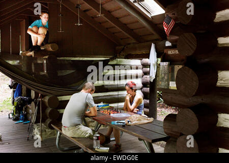 Zwei Wanderer spielen Schach, während ein Drittel Uhren. Stockfoto