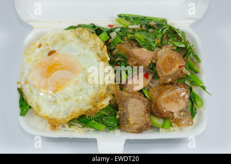 Thai Lunchpaket Menü, Schweinebauch gebraten mit Grünkohl und mit Spiegelei obenauf. Stockfoto