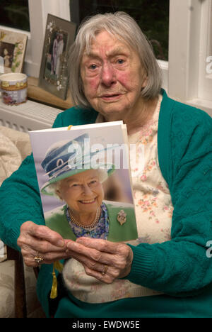 Eine 100 Jahre alte Frau zeigt stolz ihre offizielle Grußkarte von der Königin, Haslemere, Surrey, UK. Stockfoto