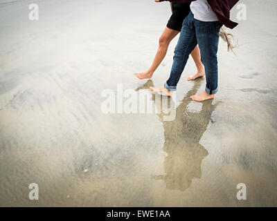 Junger Mann und junge Frau, die zu Fuß am Strand Stockfoto