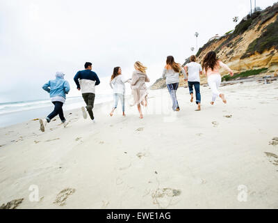 Eine Gruppe junger Männer und Frauen laufen am Strand, Spaß Stockfoto