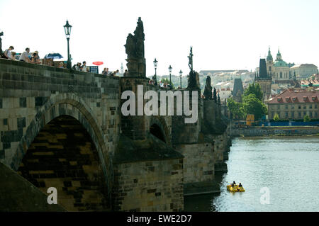 Im Windschatten der Statue besetzte Karlsbrücke, am berühmtesten von mehrere spanning Prag Moldau schwimmt ein kleines Handwerk Stockfoto