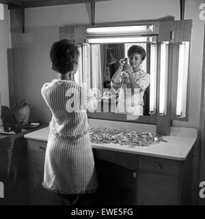 Eine Junge Frau Steht Vor Dem Spiegel Und Schminkt Sich, 1960er Jahre Deutschland. Eine junge Frau vor dem Spiegel tun ihr Make-up, Deutschland der 1960er Jahre. Stockfoto