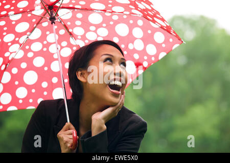 Junge Frau schützt vor Regen unter Dach Stockfoto