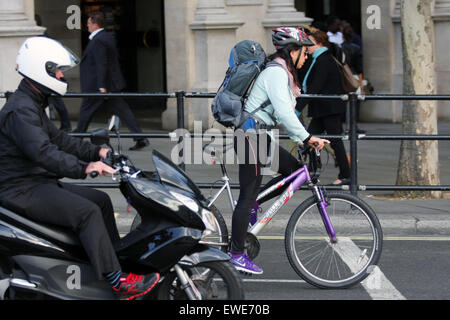 Ein Radfahrer und Motorradfahrer unterwegs entlang einer Straße in London, England Stockfoto