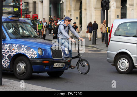 Ein Radsportler unter Verkehr am Trafalgar Square in London, England Stockfoto