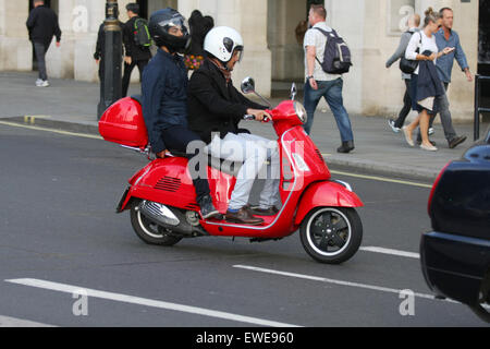 Ein Fahrer und Beifahrer fahren eines Motorrollers im Verkehr in London, England. Stockfoto