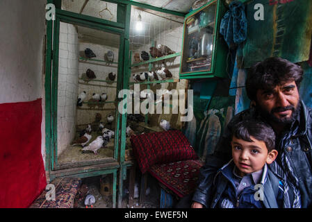 Mann mit seinem Sohn verkauft Tauben im traditionellen Shop auf Vögel Markt in Kabul, Afghanistan Stockfoto