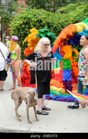 NEW YORK CITY, USA - 30. Juni 2013: Ein Hund geht mit seinem Besitzer vorbei an Drag-Queens in dramatischen Kostümen bei der Gay-Pride-Parade. Stockfoto