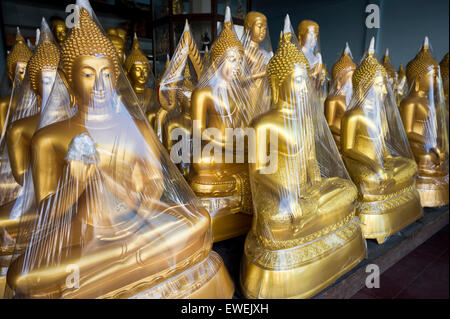 Reihen von goldenen sitzenden Buddhas verpackt in Kunststoff in einem Geschäft, spezialisiert auf Zubehör für buddhistische Tempel in Bangkok, Thailand Stockfoto