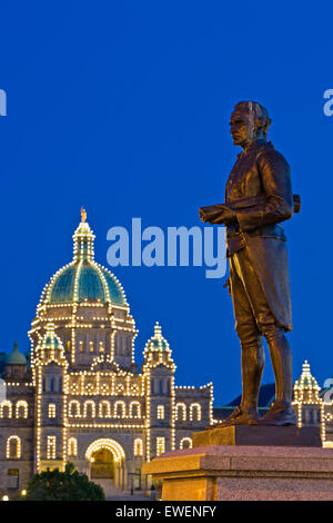 Captain James Cook-Statue in Victorias Inner Harbour in der Dämmerung mit beleuchteten BC Parlamentsgebäude im Hintergrund Stockfoto