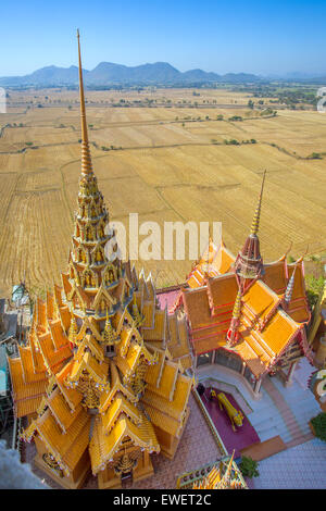 Ein Blick von oben auf die Pagode, goldene Buddha-Statue mit Reisfeldern und Bergen, Wat Tham Sua(Tiger Cave Temple), Tha Moun Stockfoto