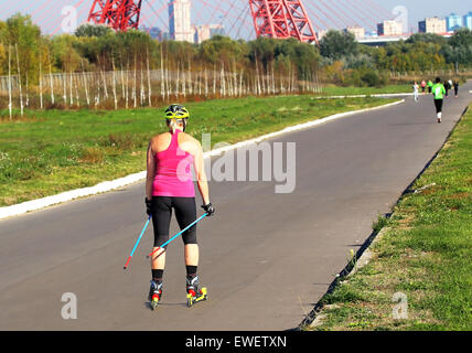 Mädchen in ein Sport-Anzug und Helm rollerblading Stockfoto