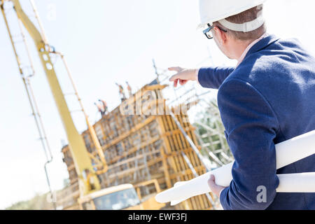 Rückansicht des Architekten halten Baupläne unter Hinweis auf Baustelle Stockfoto