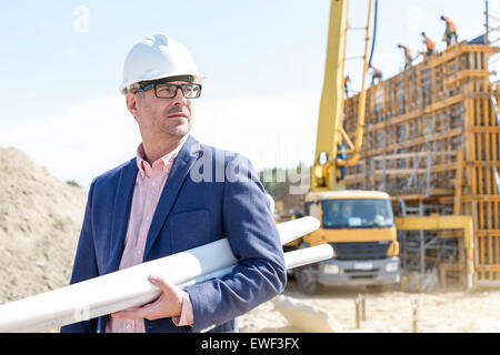 Zuversichtlich Architekten halten aufgerollt Blaupausen auf Baustelle Stockfoto