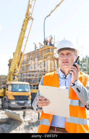 Männlichen Vorgesetzten mit Walkie-talkie gedrückter Zwischenablage auf Baustelle Stockfoto