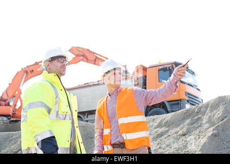 Ingenieur, zeigen etwas an Kollegen während der Diskussion auf Baustelle gegen klaren Himmel Stockfoto