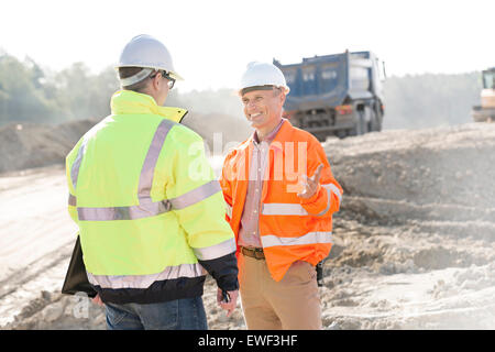 Glücklich Ingenieur im Gespräch mit Kollegen auf Baustelle am sonnigen Tag Stockfoto