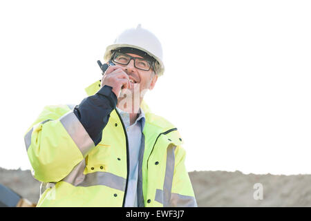Glücklich Supervisor mit Walkie-talkie auf Baustelle gegen klaren Himmel Stockfoto