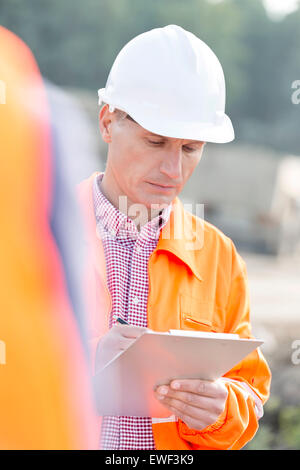 Vorgesetzten schriftlich auf Zwischenablage auf Baustelle Stockfoto