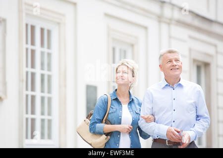 Glückliches Ehepaar mittleren Alters stehend mit Arm in Arm vor Gebäude Stockfoto