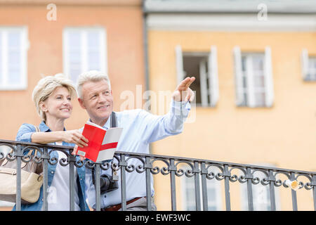 Glücklicher Mann zeigen etwas auf eine Frau mit Reiseführer in Stadt Stockfoto