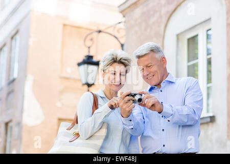 Glückliches Ehepaar mittleren Alters, betrachten von Bildern auf digitalen Kamera in Stadt Stockfoto
