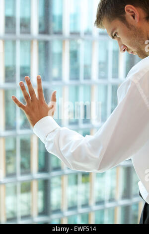 Junge Caucassian Geschäftsmann gegen Bürofenster Stockfoto