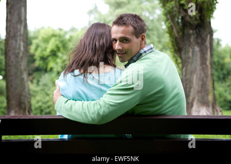 Porträt des jungen Mann mit Freundin sitzen auf Bank Stockfoto