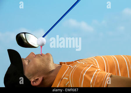 Mann Ausgleich Golfball am Abschlag in den Mund Stockfoto