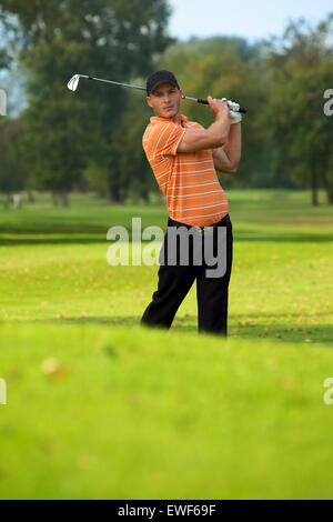 Junger Mann schwingenden Golf club Stockfoto