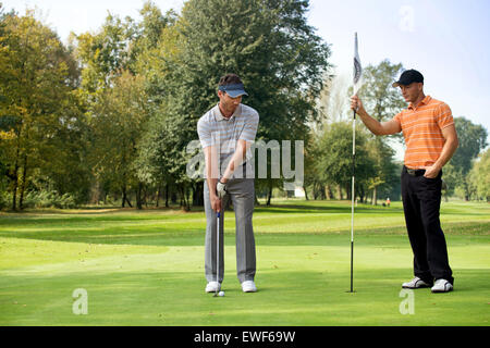 Junger Mann mit seinem Freund in Golfplatz Golf zu spielen Stockfoto