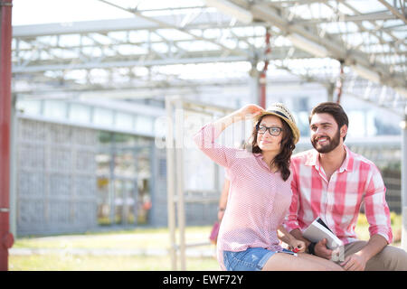 Brautpaar sitzend auf Bank unter Schatten wegschauen Stockfoto