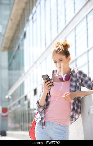 Junge Frau mit Smartphone vor Bürogebäude Stockfoto