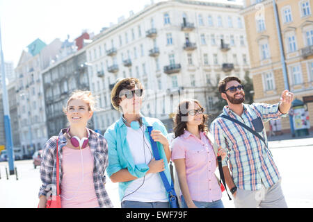 Glücklicher Mann zeigen etwas an männliche und weibliche Freunde auf Stadt Straße Stockfoto