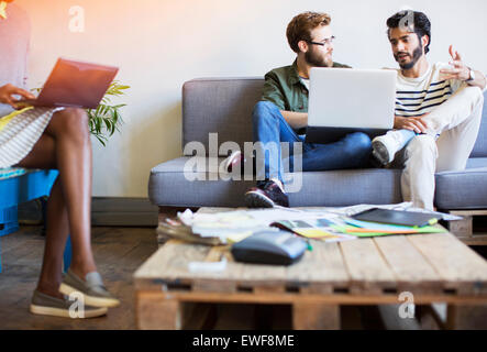 Lässige Geschäftsleute sprechen und mit Laptop auf sofa Stockfoto