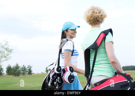 Lächelnde Golfspielerin Gespräch mit Freund am Golfplatz Stockfoto