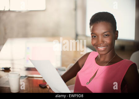 Porträt lächelnd Geschäftsfrau mit Papierkram im Büro Stockfoto