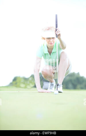 Frau mittleren Alters mit dem Ziel Kugel am Golfplatz Stockfoto