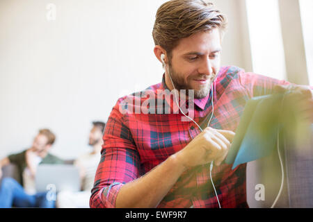 Lässige Geschäftsmann mit Kopfhörer und digital-Tablette im Büro Stockfoto