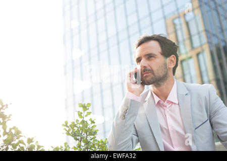 Geschäftsmann Beantwortung Handy vor Bürogebäude Stockfoto