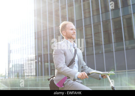 Geschäftsmann Reiten Fahrrad vor Bürogebäude Stockfoto